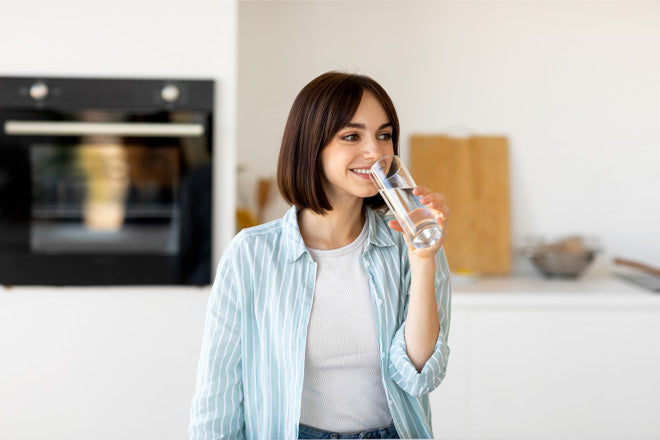 Young healthy Woman drinking water from a glass in modern a kitchen