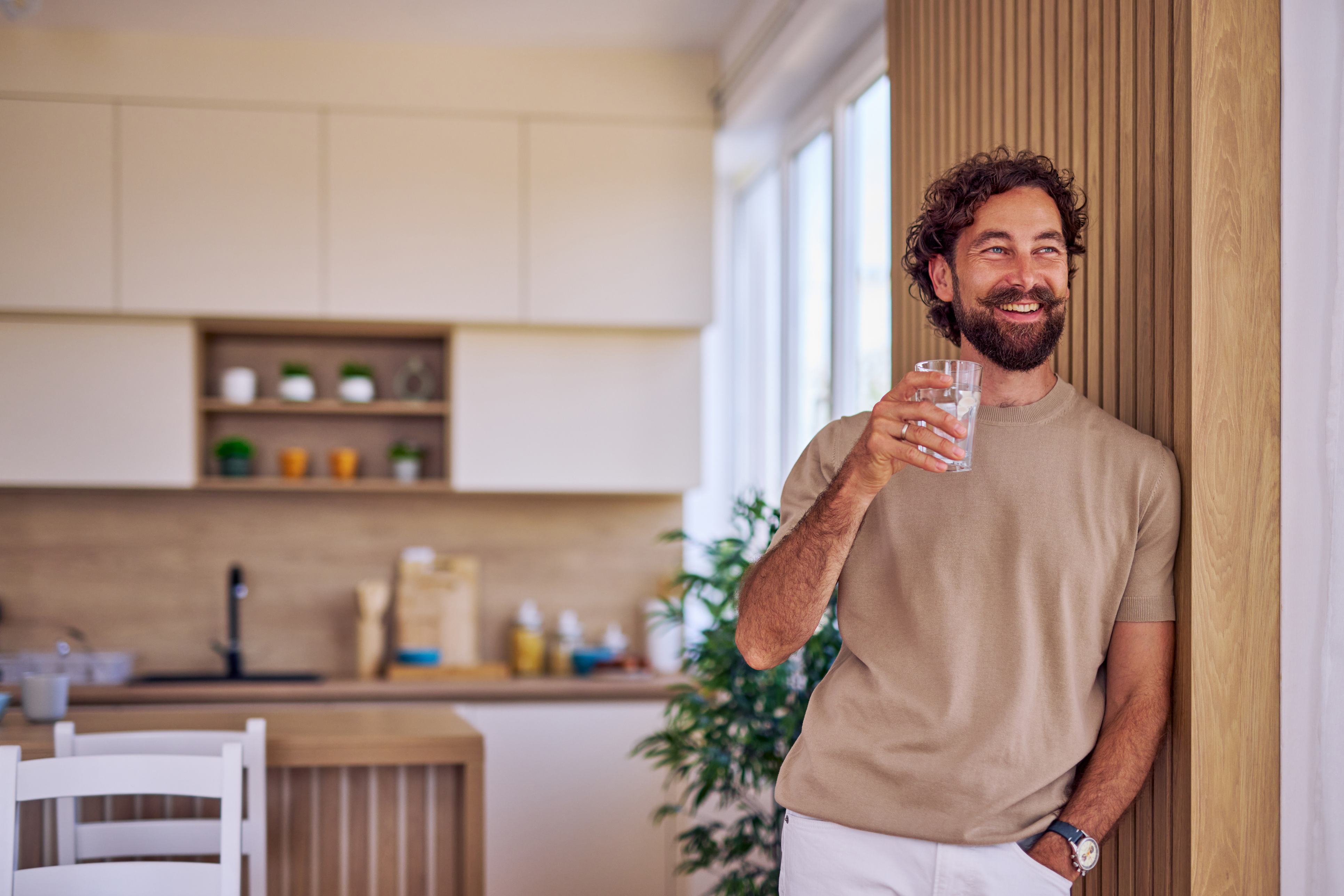 Man holding a glass of water in a modern kitchen