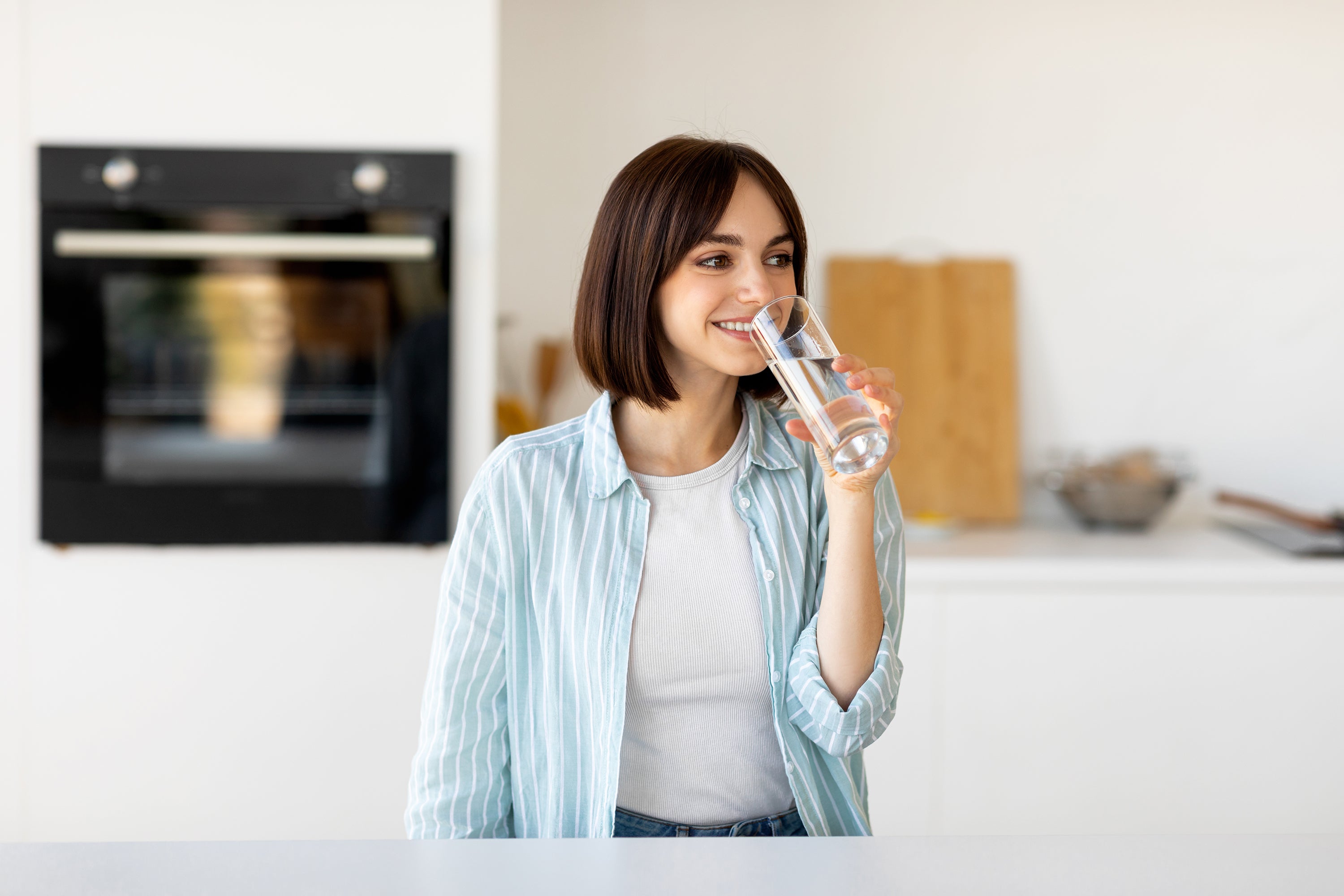 Woman drinking water from a glass in modern a kitchen